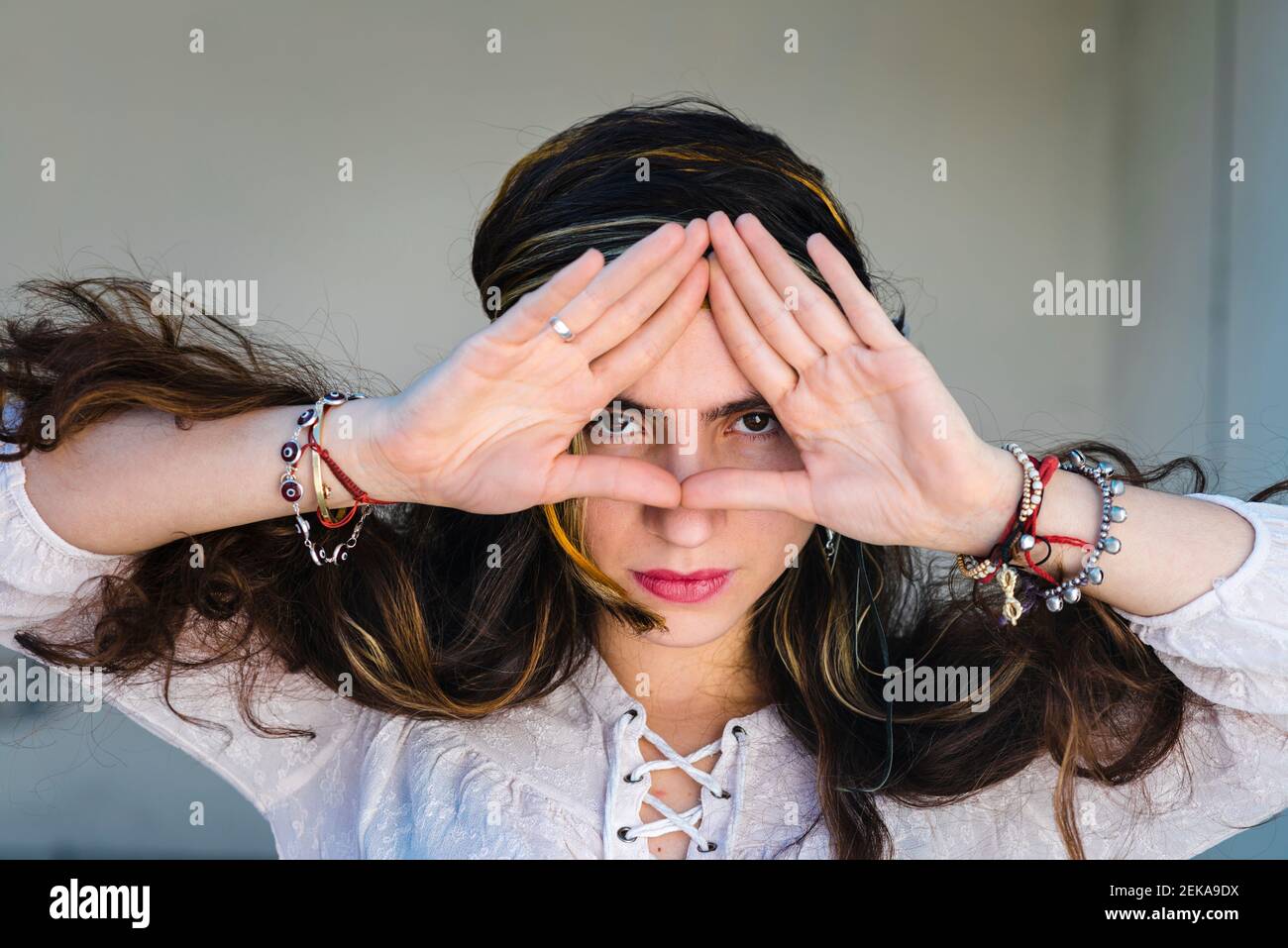 Close-up of hippie woman greeting while standing against wall Stock Photo
