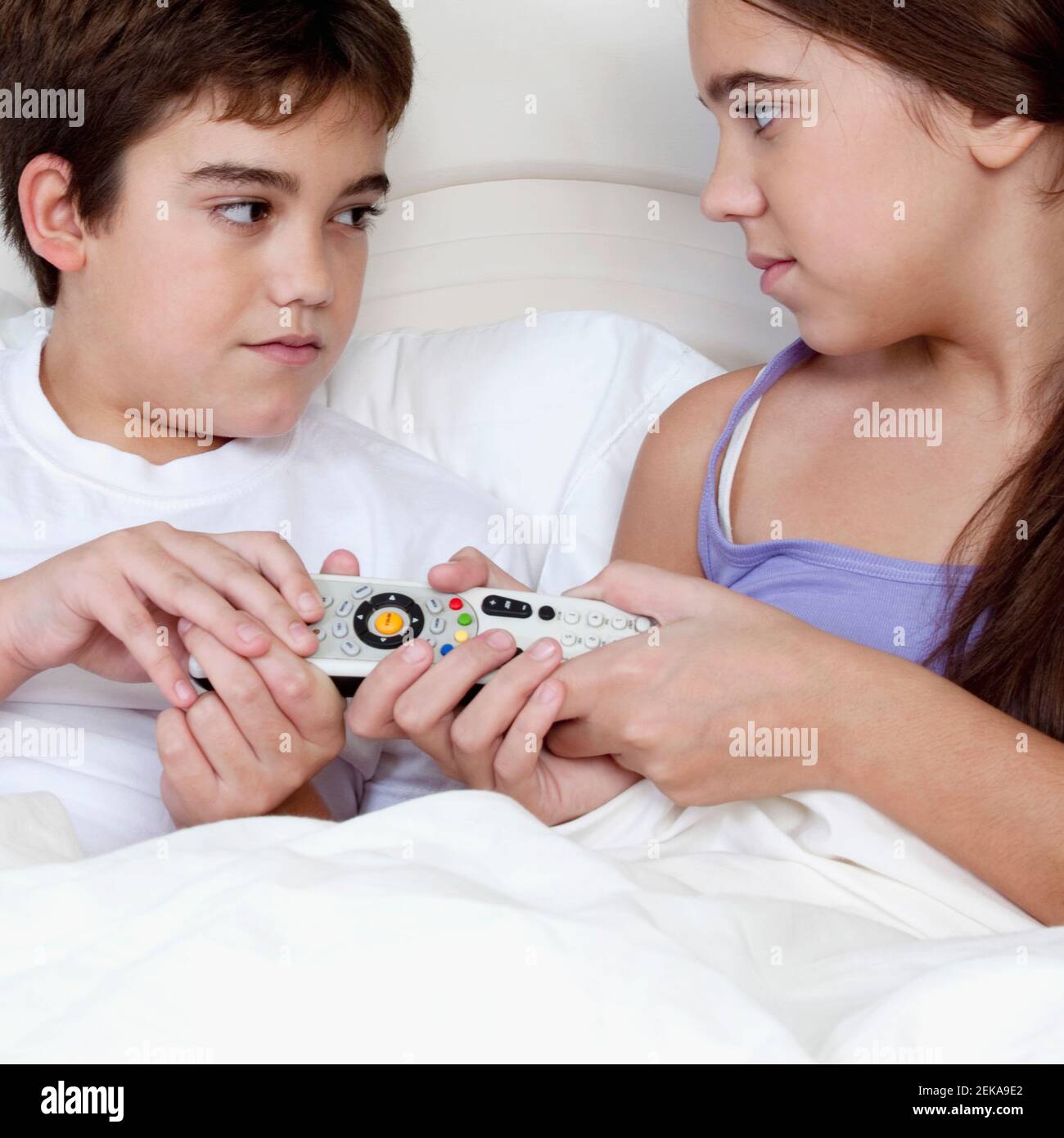 Boy lying in the bed with his sister and arguing over a remote control Stock Photo