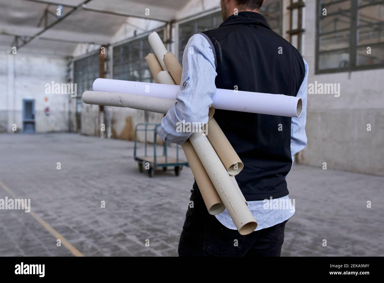 Male architect with cardboards standing in constructing building Stock Photo