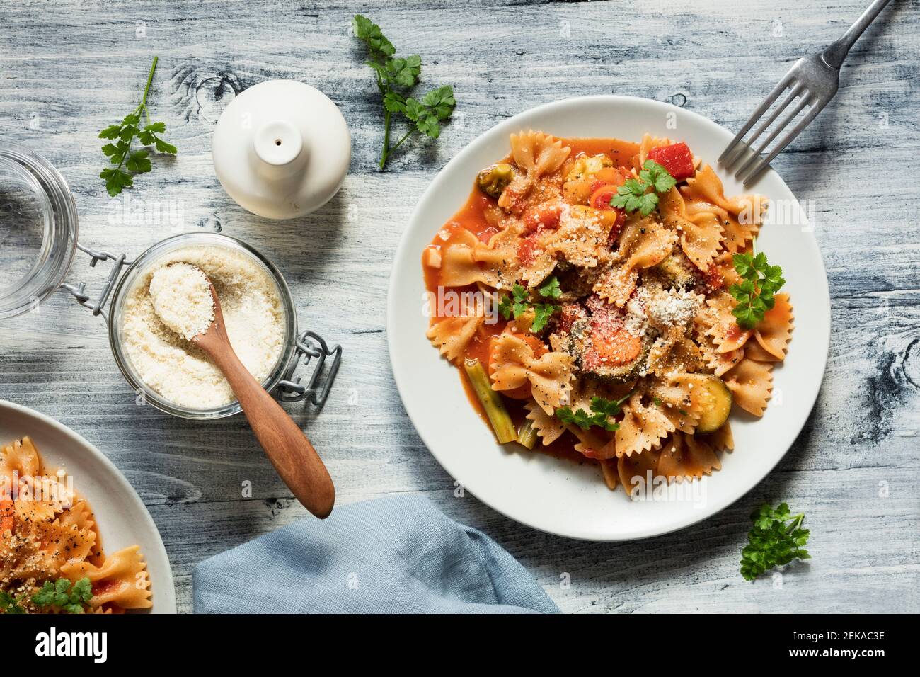 Two plates of bow tie pasta with vegetables and vegan Parmesan Stock