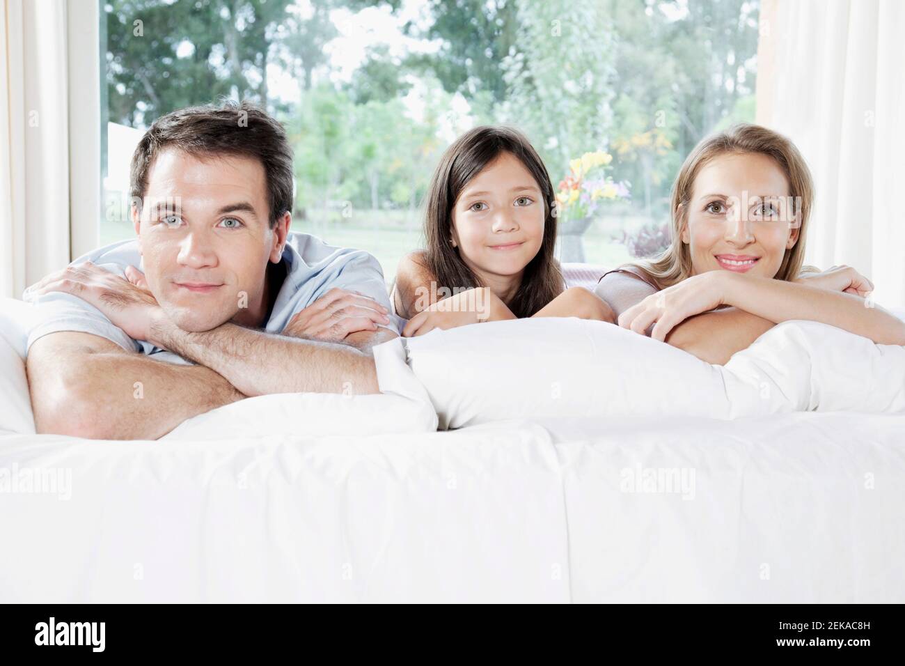 Girl with her parents lying on the bed Stock Photo