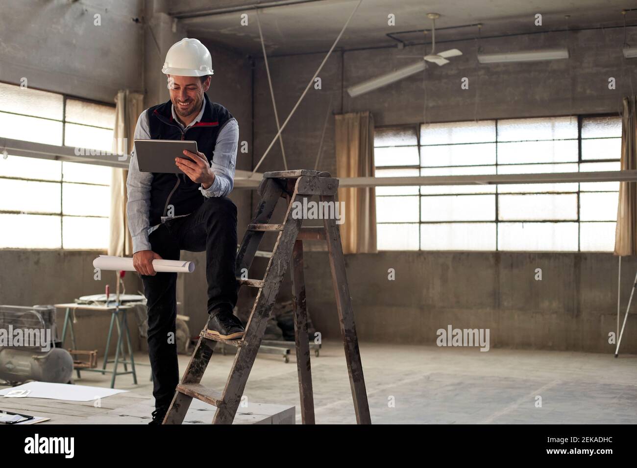 Smiling male building contractor using digital tablet while standing inside site Stock Photo