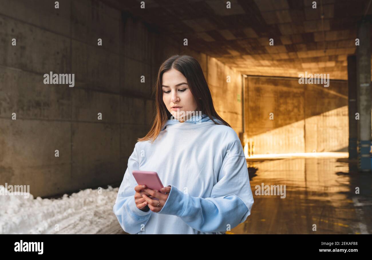 Woman using mobile phone while standing against tunnel Stock Photo