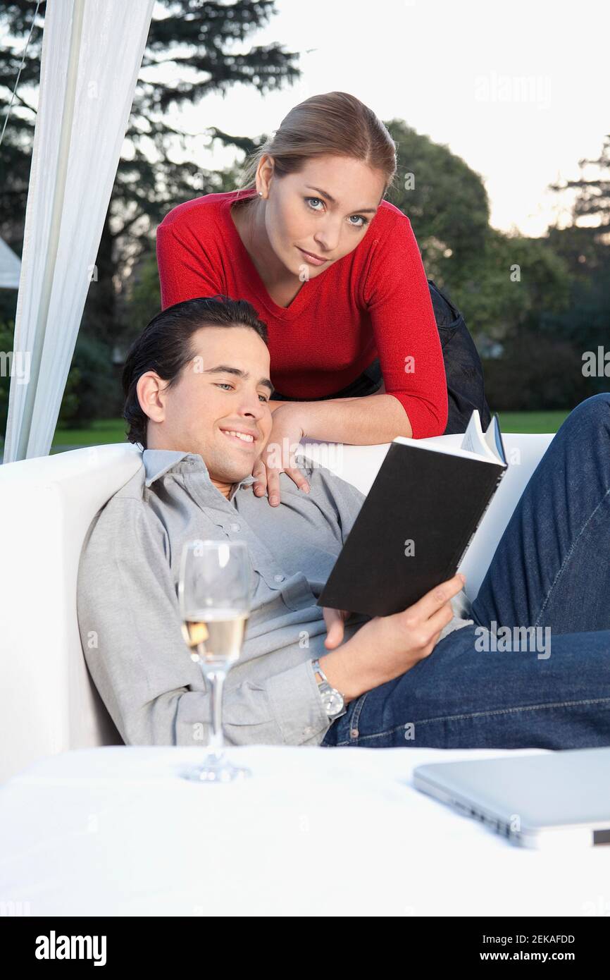 Man reading a book with his wife behind him Stock Photo - Alamy