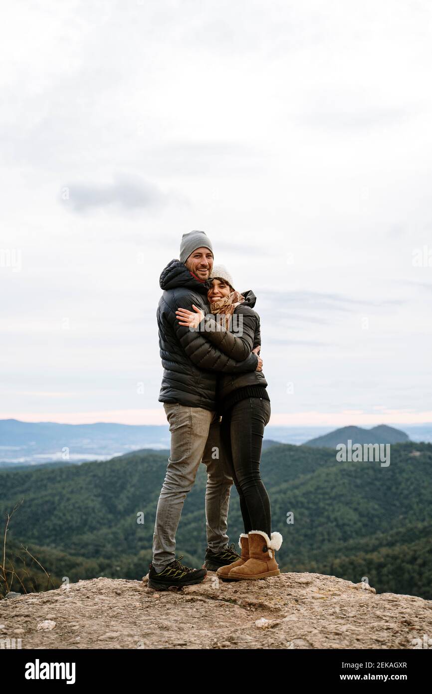 Happy couple hugging each other at viewpoint against sky Stock Photo
