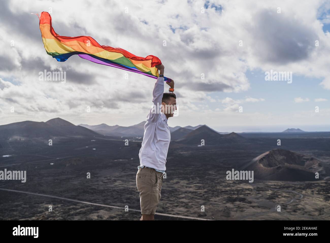 Gay young male tourist with an LGBT flag at El Cuervo Volcano, Lanzarote, Spain Stock Photo