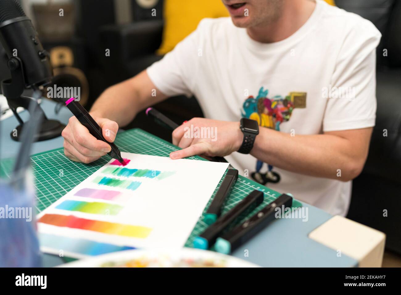 Male artist teaching color gradient using coloring pen while live streaming at home Stock Photo