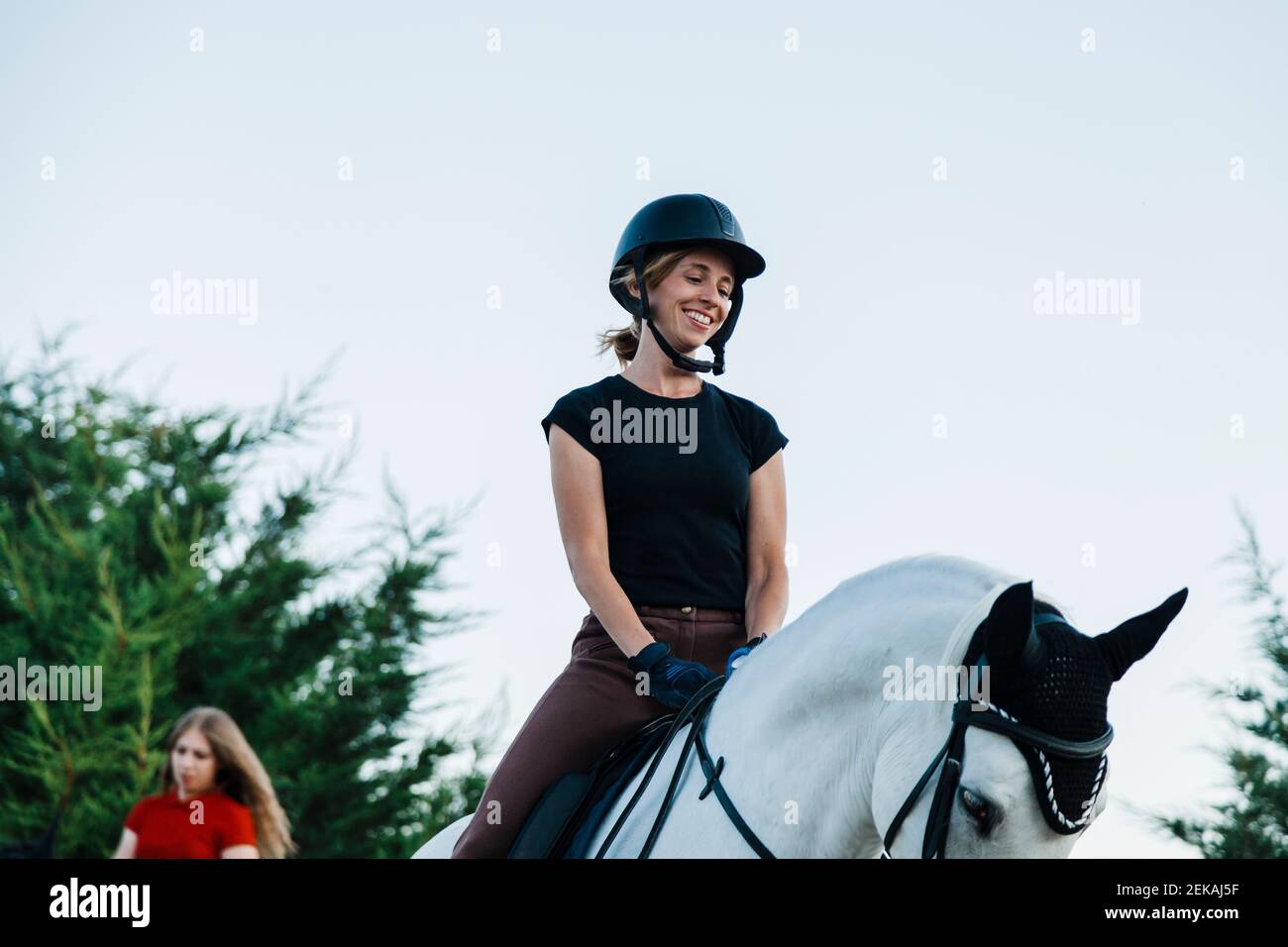 Smiling woman looking at horse while riding on weekend Stock Photo