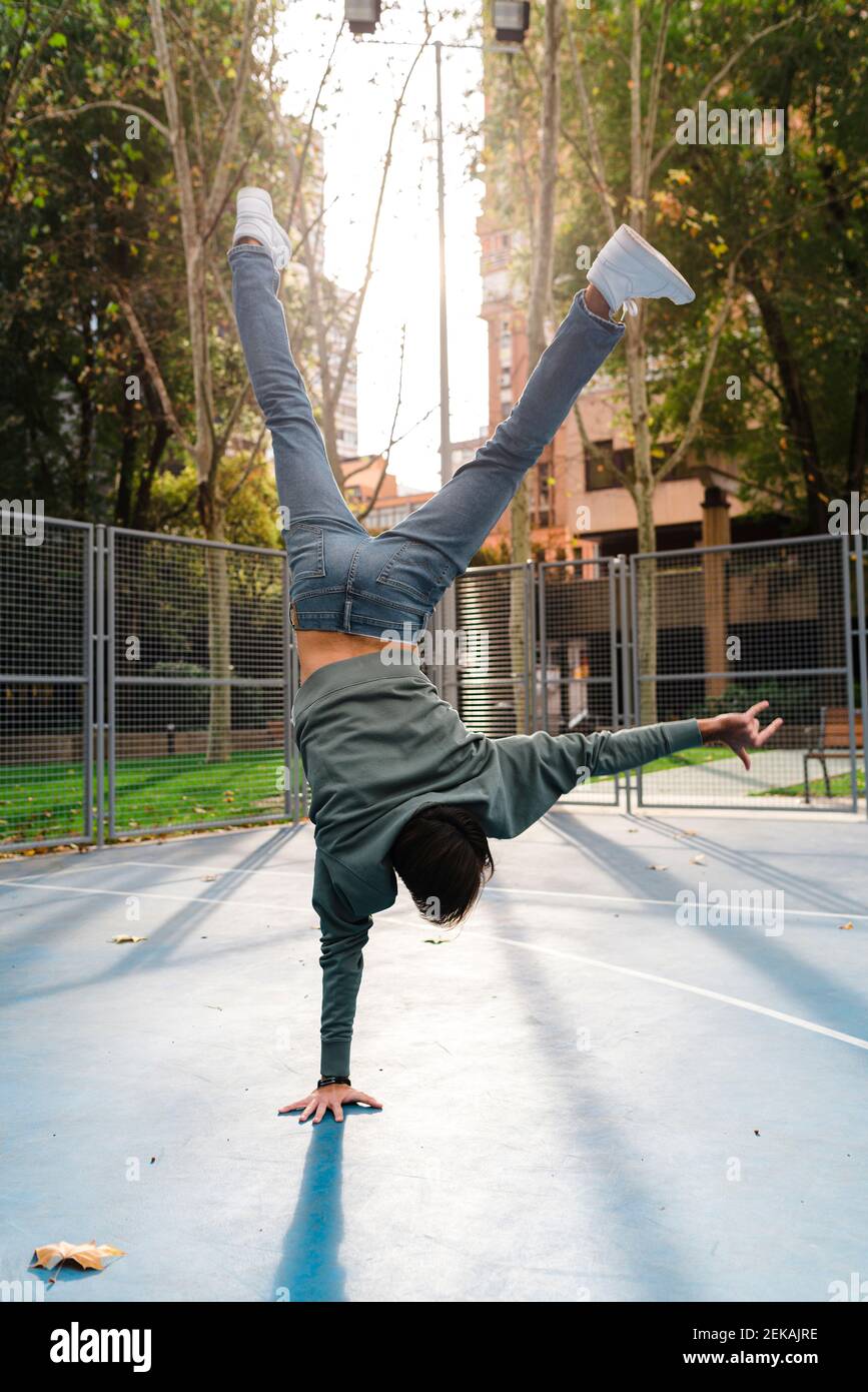 Acrobatic man with horn sign doing handstand at basketball court in