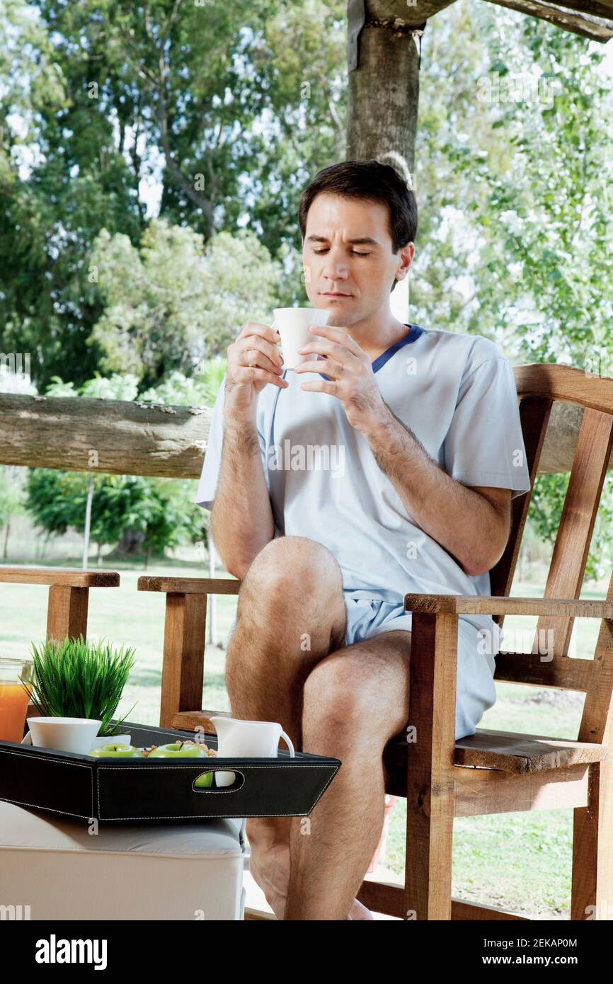 Man sitting on a chair and drinking tea Stock Photo