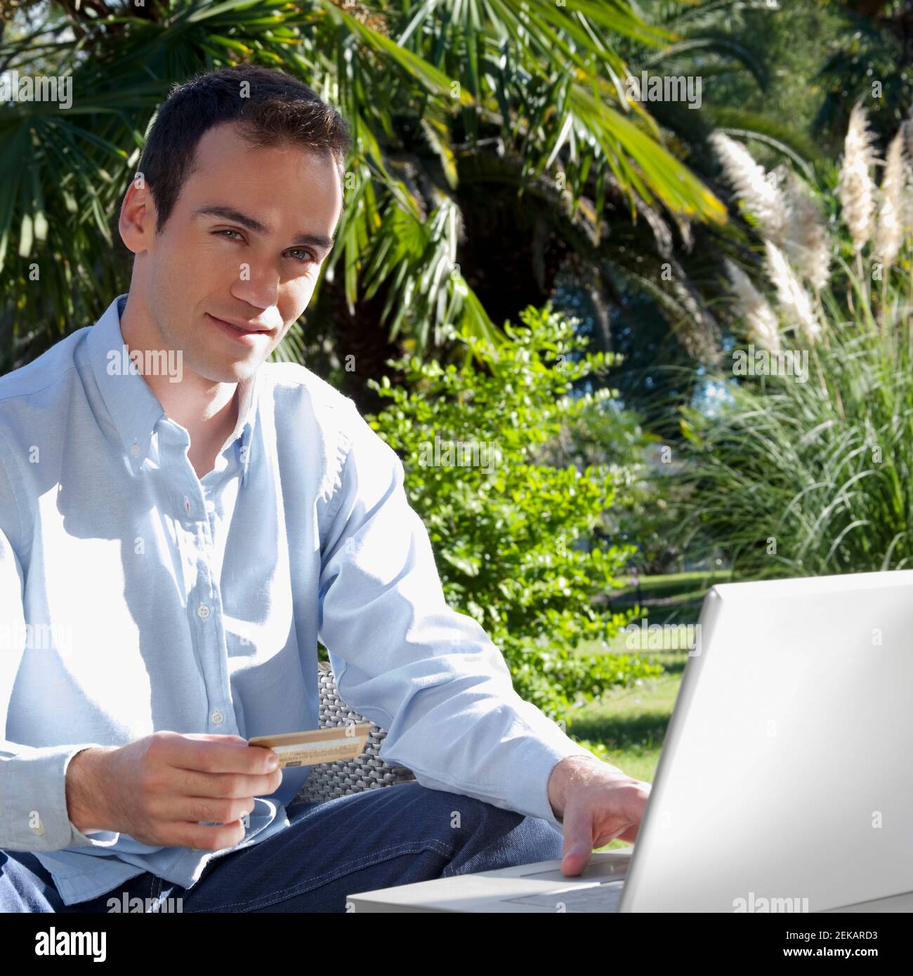 Man holding a credit card and using a laptop Stock Photo