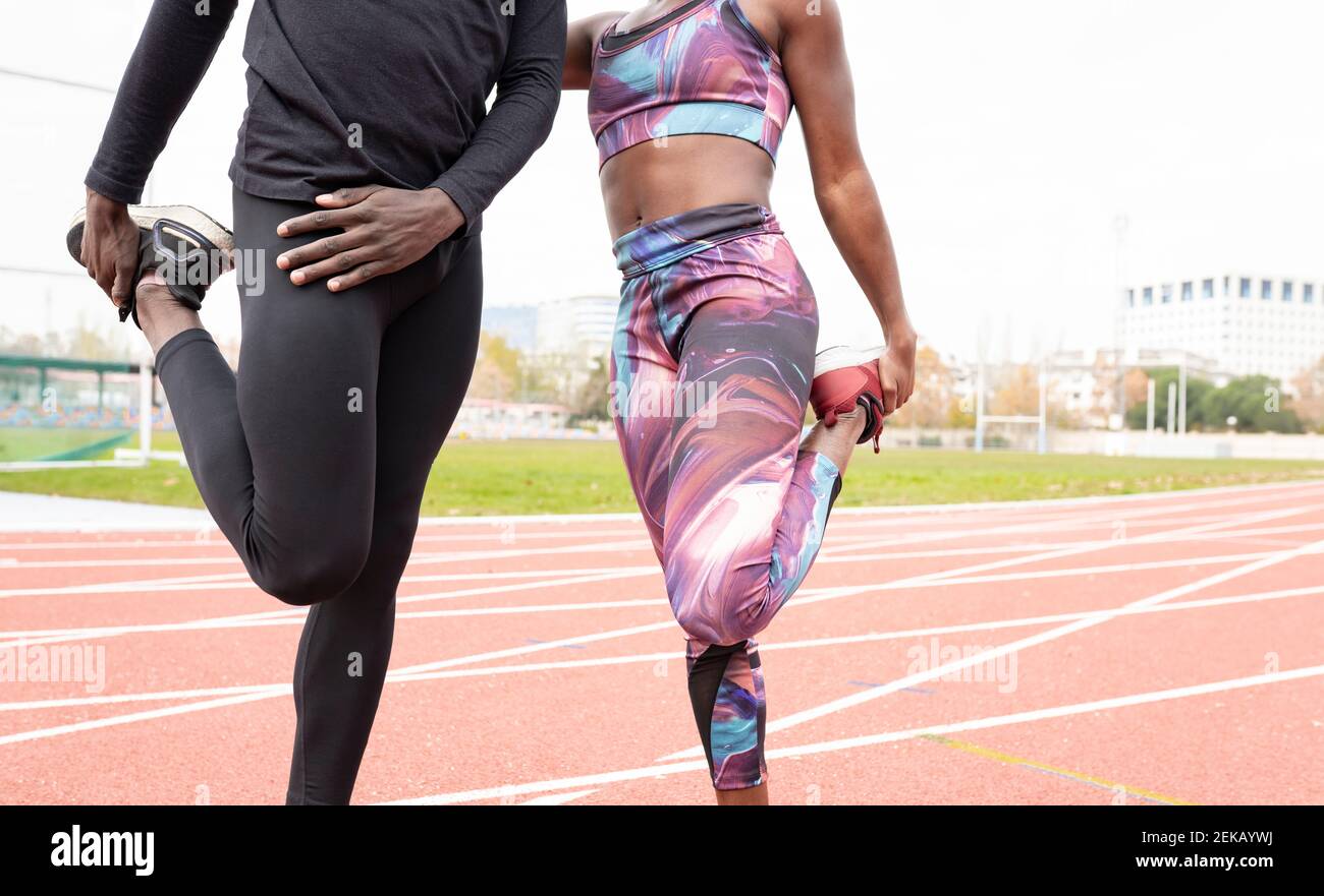 Male and female sportsperson stretching while standing on running track Stock Photo