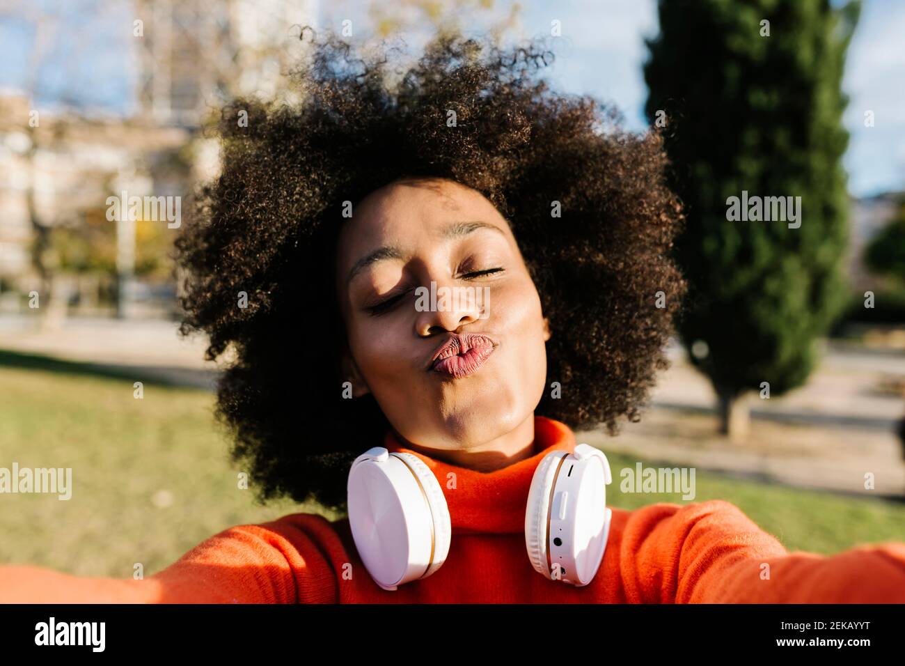 Young woman with eyes closed puckering while taking selfie at park Stock Photo
