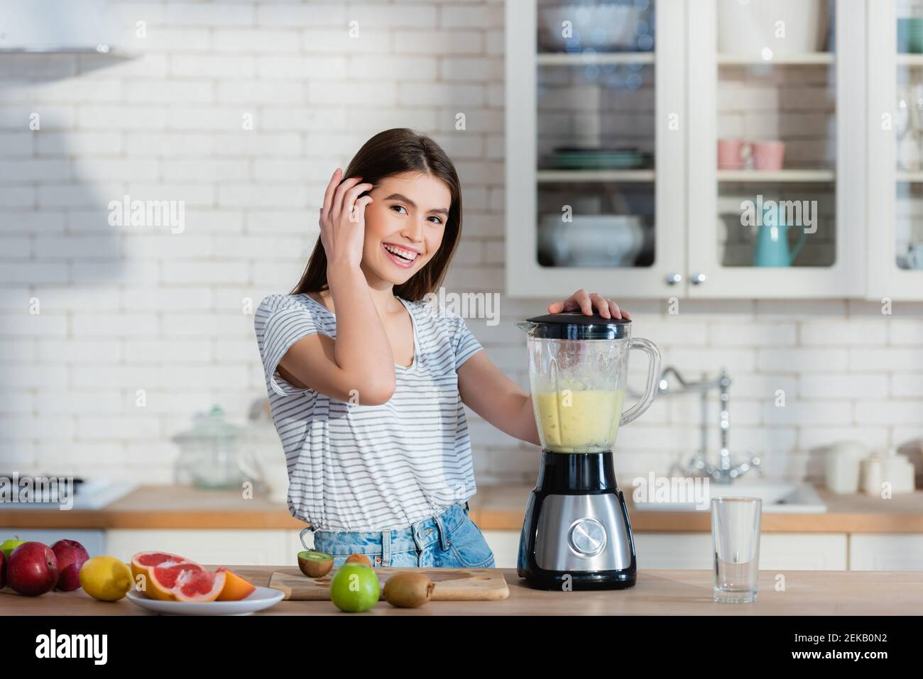 happy woman looking at camera while preparing fruit smoothie in blender  Stock Photo - Alamy