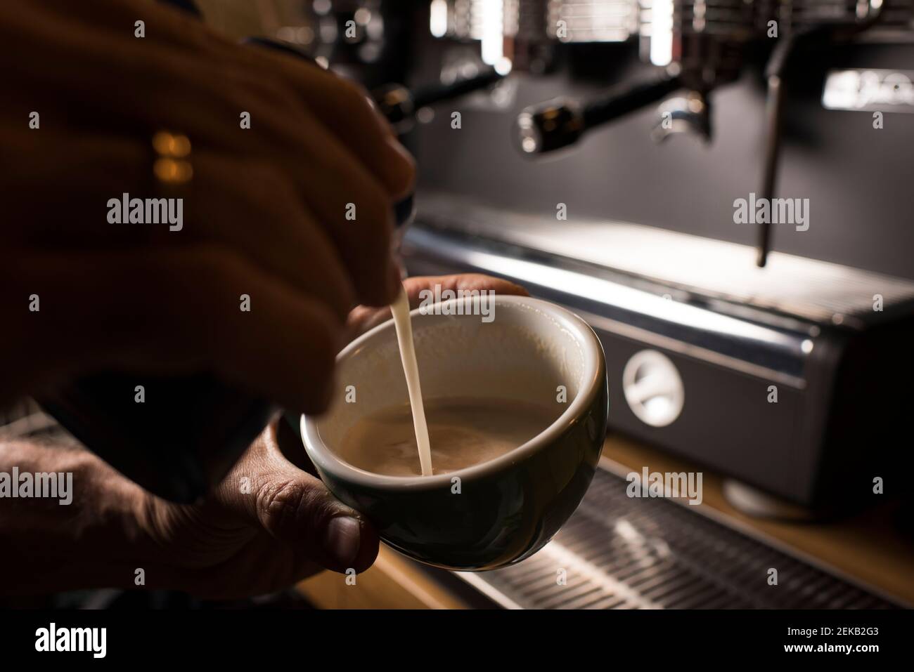 Barista pouring milk while making coffee at cafe Stock Photo