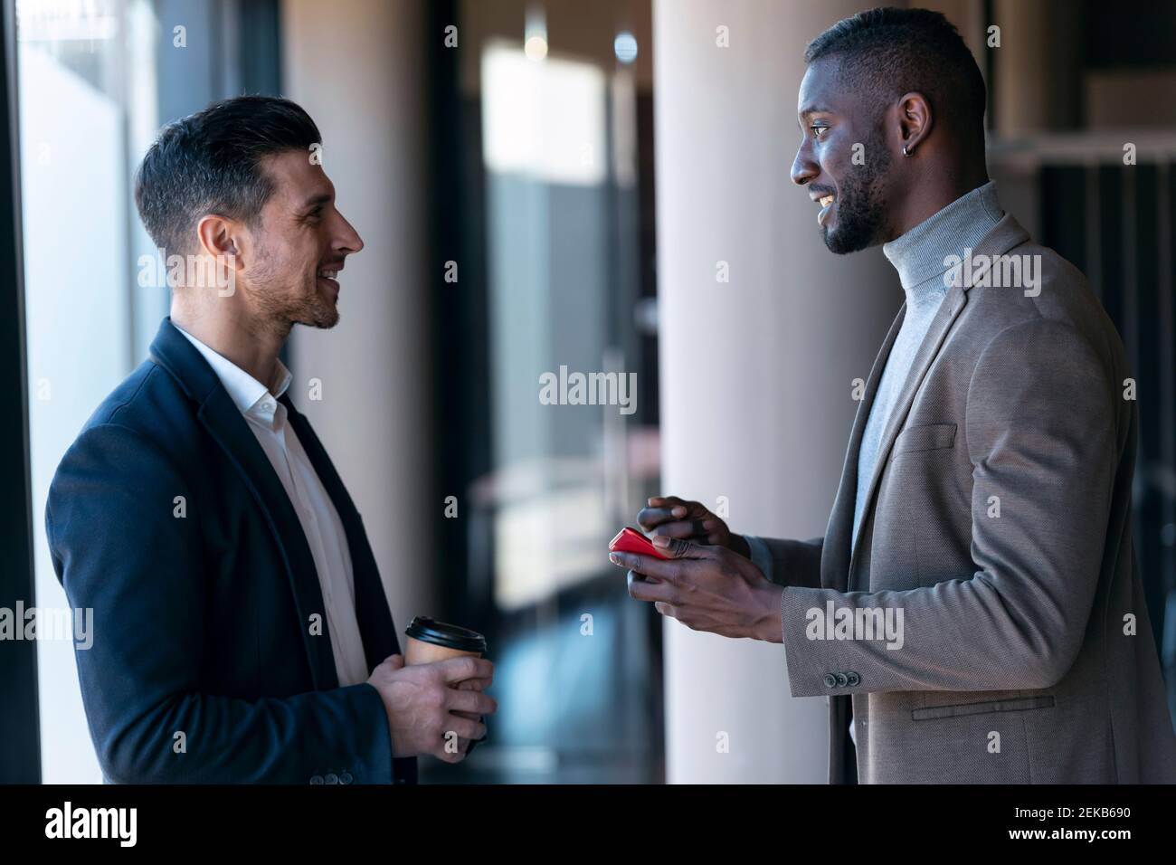 Smiling businessmen having discussion while standing in office Stock Photo