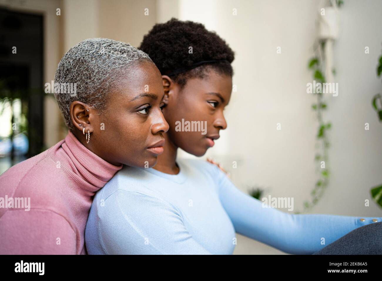 Thoughtful female friends looking away at home Stock Photo