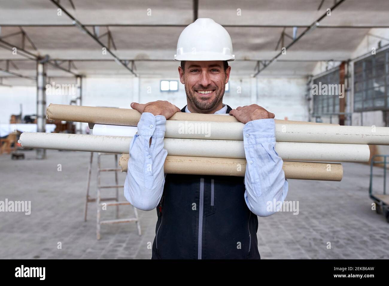 Smiling male architect holding cardboards while standing in building Stock Photo