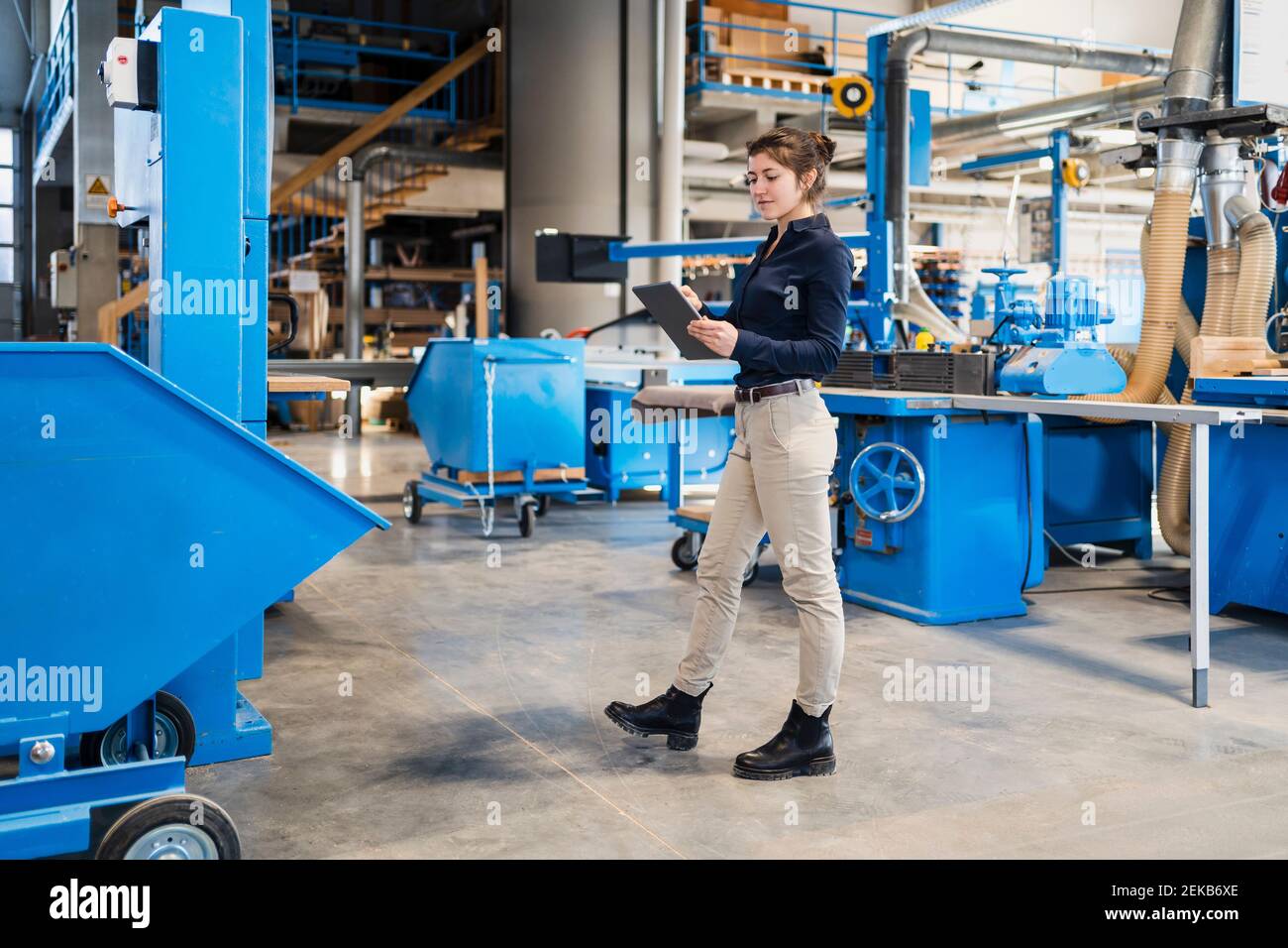 Businesswoman using digital tablet while walking at industry Stock Photo