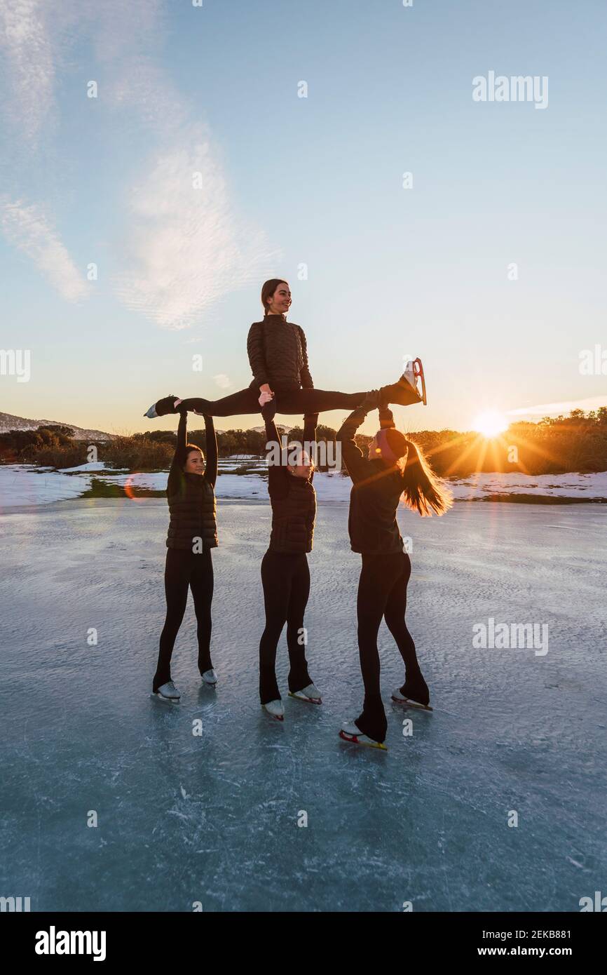 Female figure skaters practicing on frozen lake at sunset Stock Photo ...