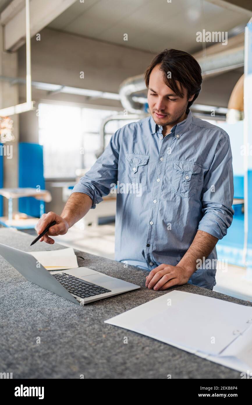 Young businessman using laptop while working at industry Stock Photo
