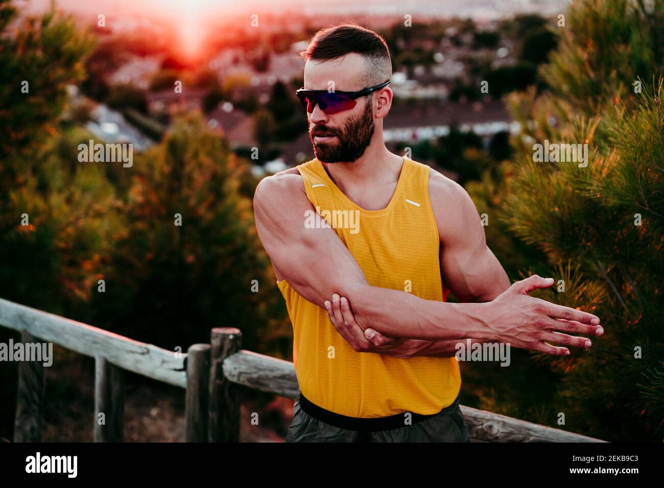 Male athlete looking away while stretching elbow at sunset Stock Photo