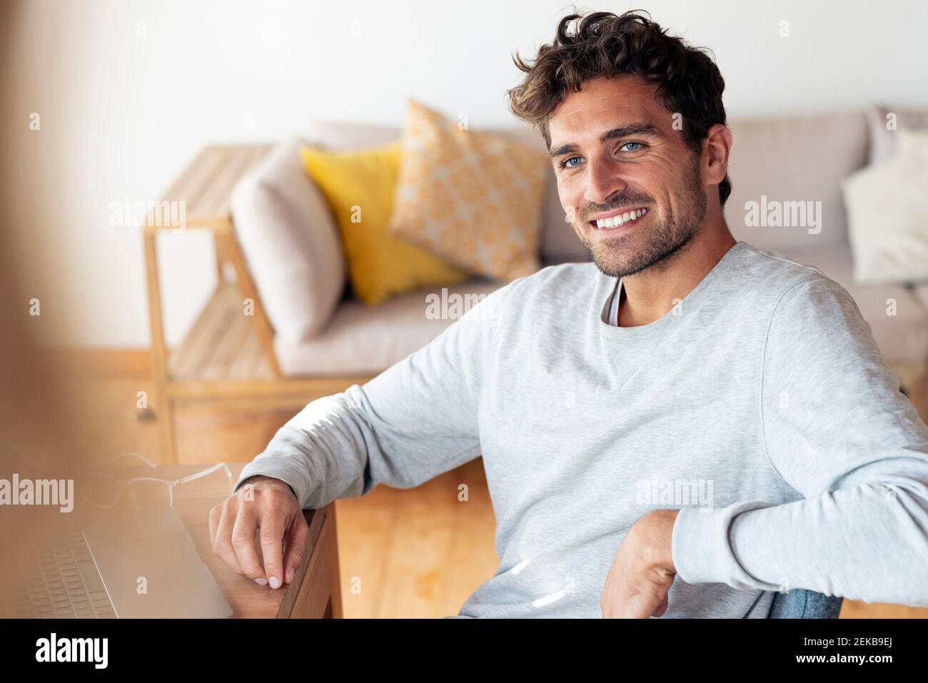 Smiling man looking away while sitting at home Stock Photo