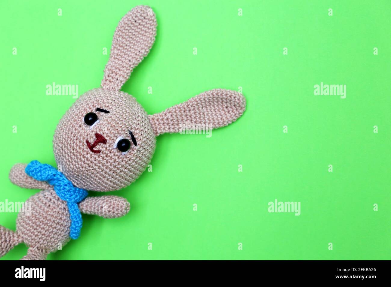Easter Bunny on green background. Greeting card with knitted toy rabbit with free copy space Stock Photo