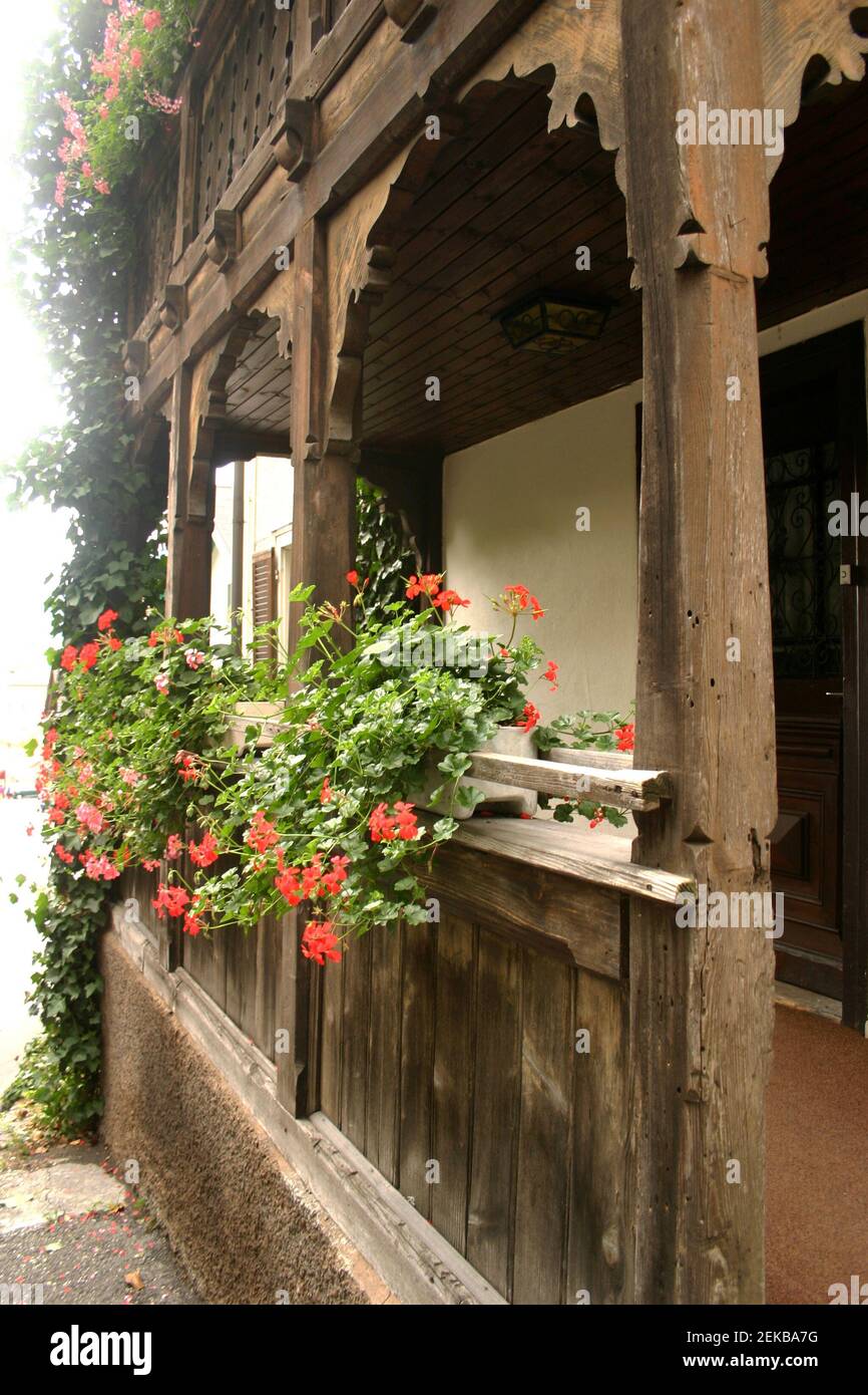 Facade of a house in Liechtenstein, with a beautifully carved wooden porch and decorative flowers Stock Photo