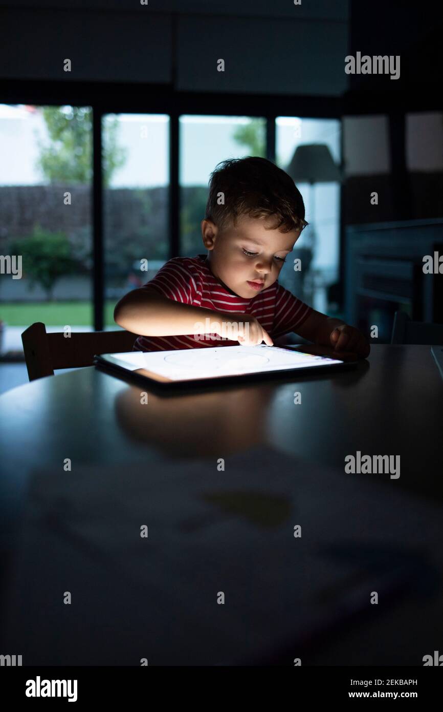 Boy using digital tablet while sitting at table in home Stock Photo