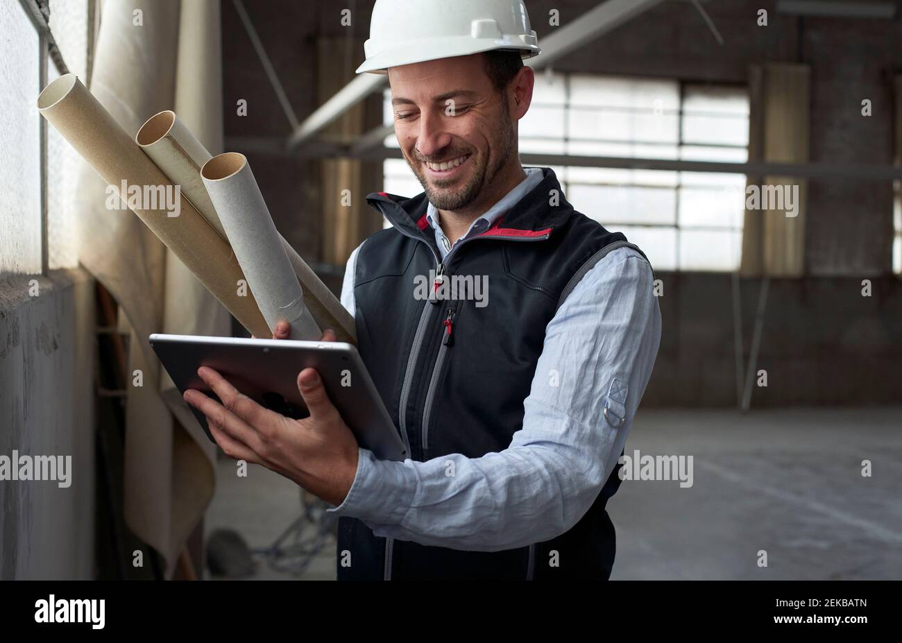 Smiling building contractor using digital tablet while standing at construction site Stock Photo