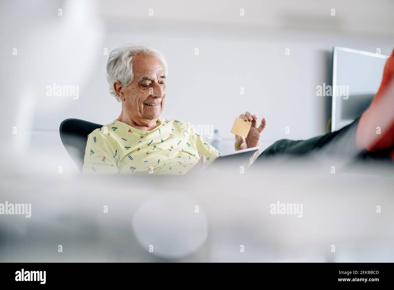 Smiling businessman using digital tablet while sitting at office Stock Photo