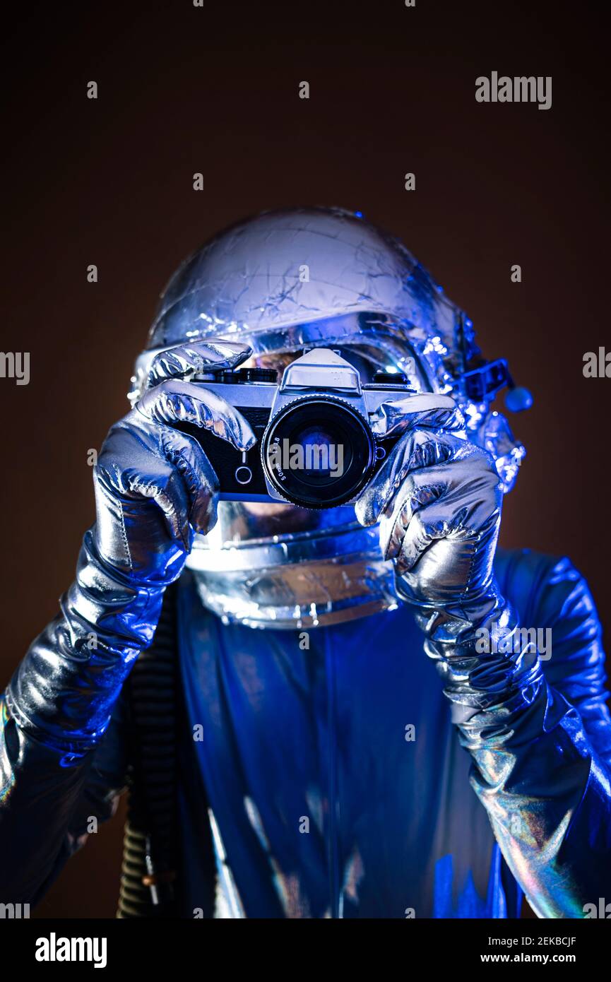 Astronaut in space suit pointing at smart phone against colored ...