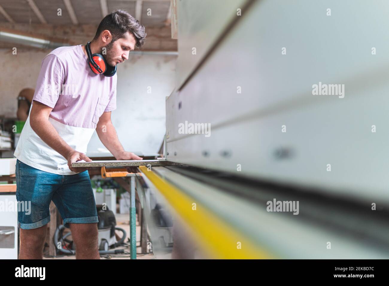 Male craftsperson holding plank while working in workshop Stock Photo