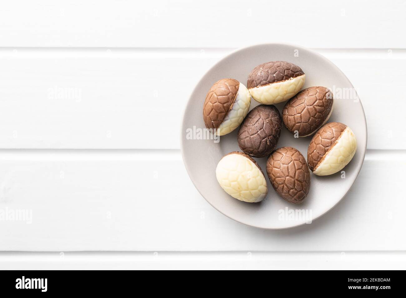 Chocolate easter eggs. Sweet candy eggs on white table. Top view. Stock Photo
