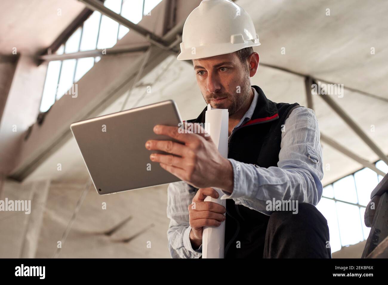 Serious male engineer using digital tablet while standing in building at site Stock Photo