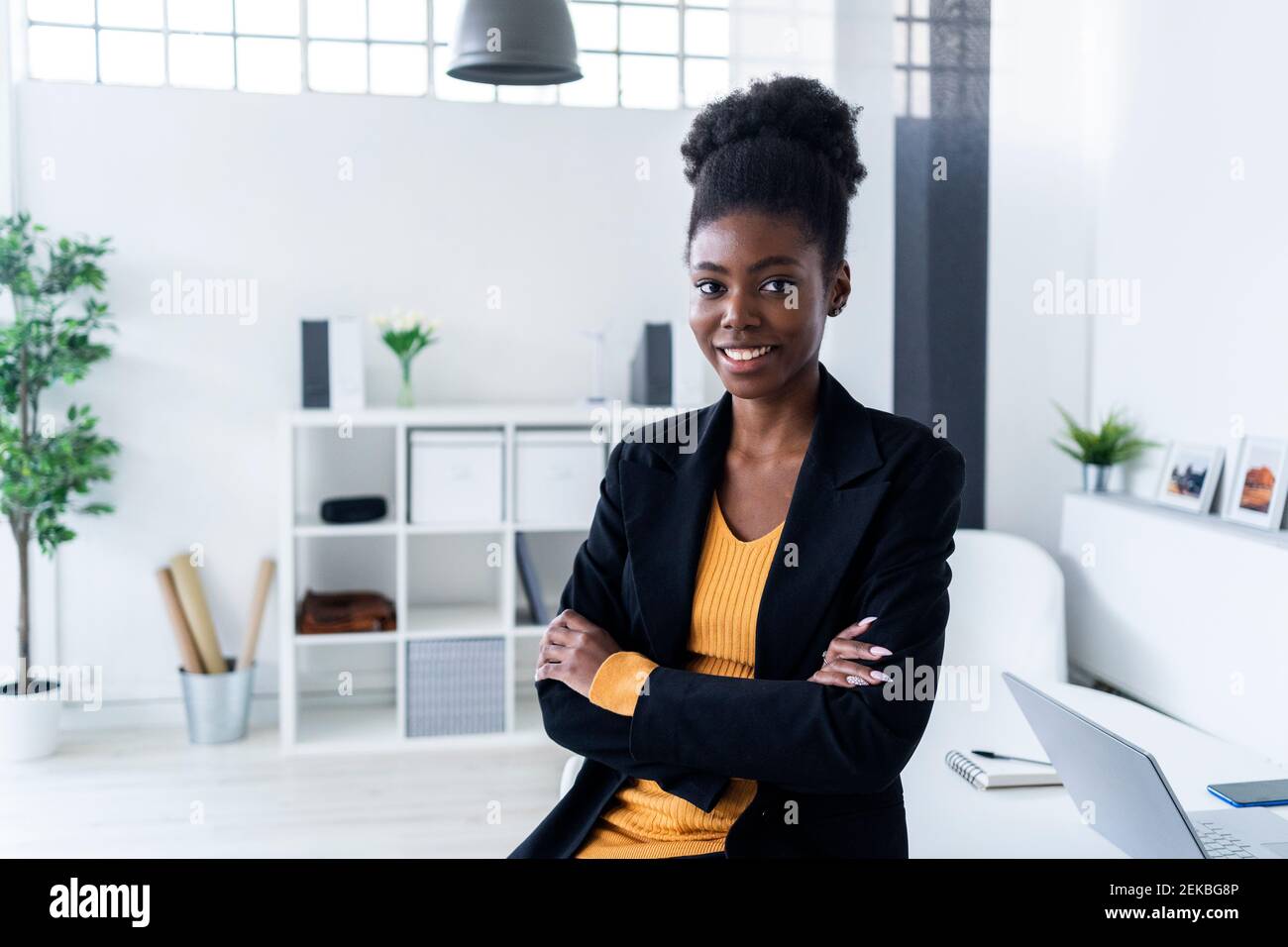 Smiling young Afro businesswoman with arms crossed in office Stock ...