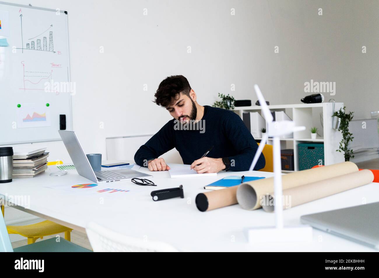 Young businessman writing at desk in creative office Stock Photo