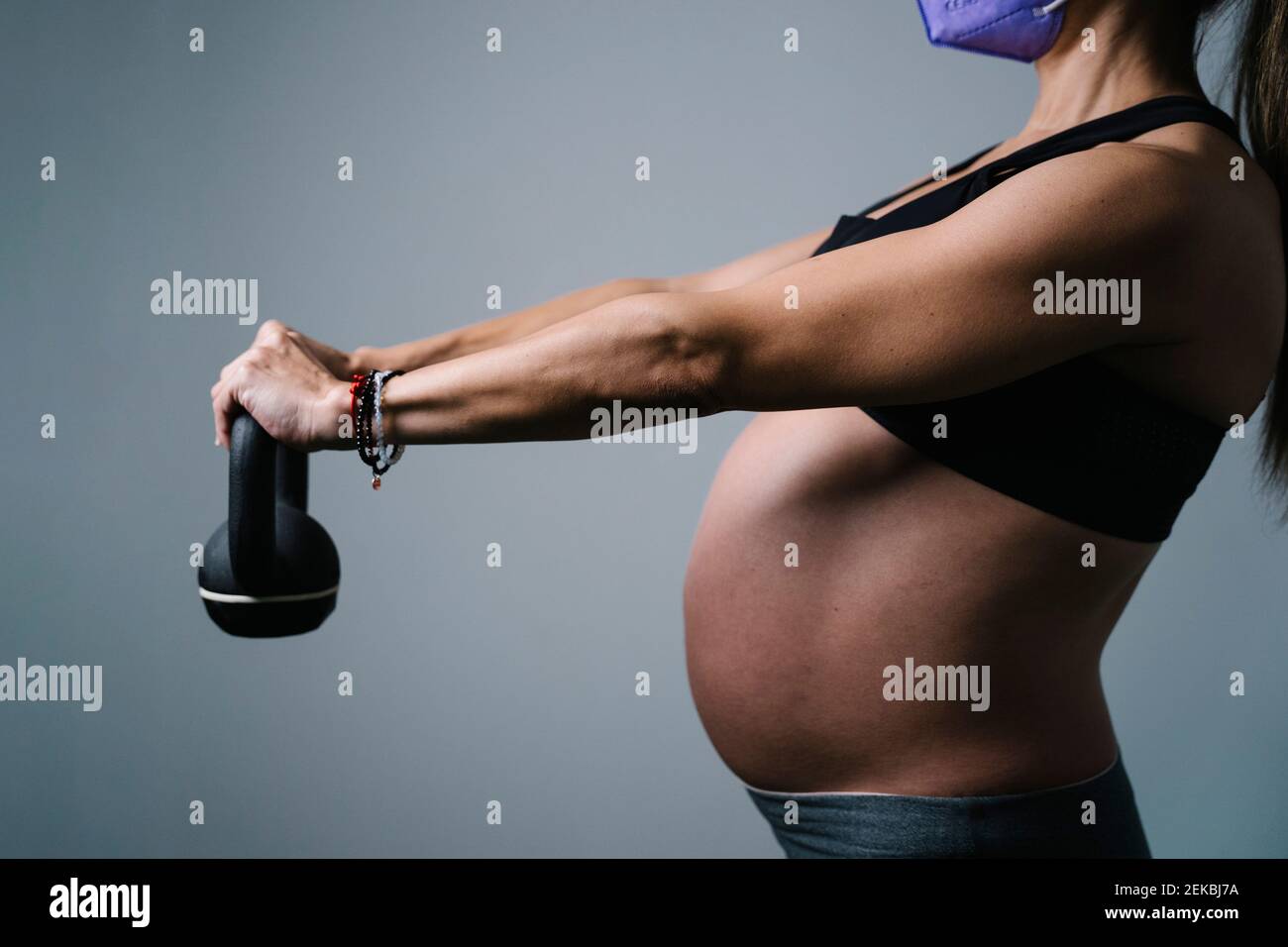Pregnant woman holding kettlebell while exercising at hospital Stock