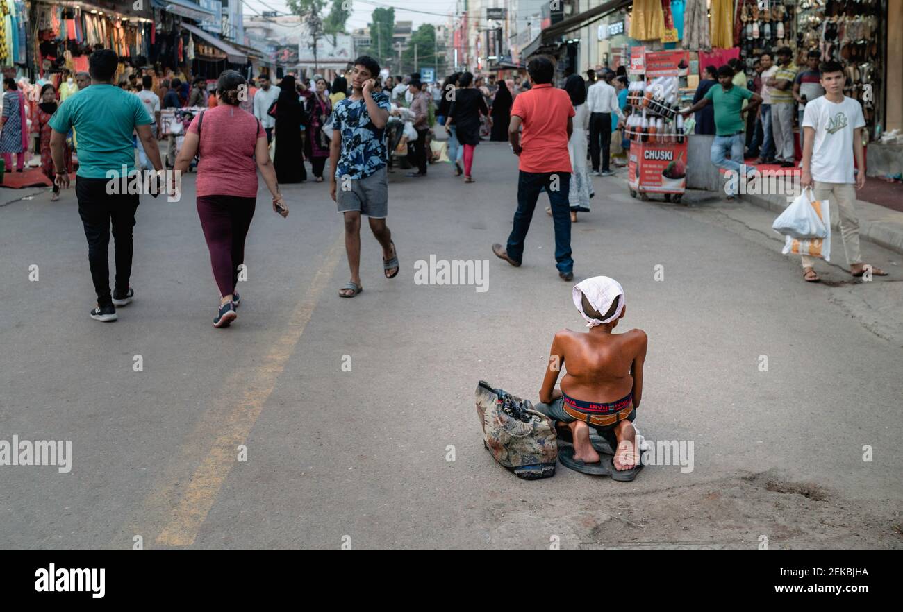 Chronically disabled poor man seeking alms along street in busy market place in Delhi, Uttar Prades Stock Photo