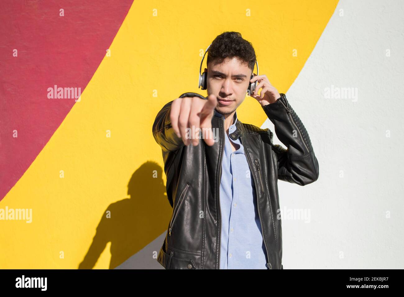 Smiling young man throwing papers while standing against colorful wall Stock Photo