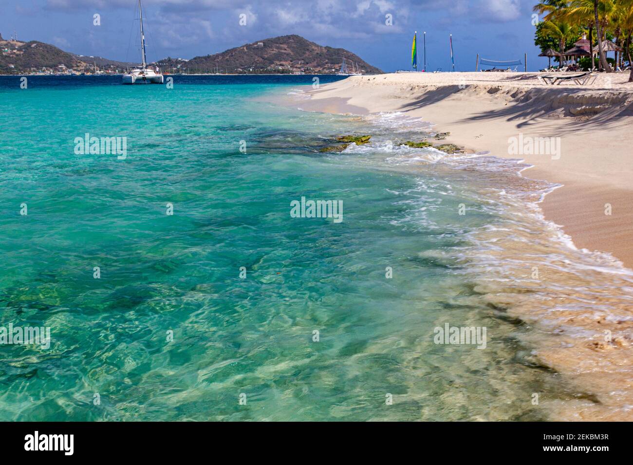 Palm Island Waters Edge-View of Casuarina Beach With Turquoise Caribbean Sea, Gentle Waves, Palm Trees, Yachts and Union island with Blue Sky #2 Stock Photo