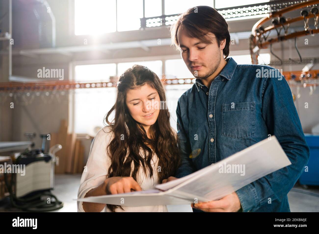 Smiling colleagues discussing document while standing at industry Stock Photo