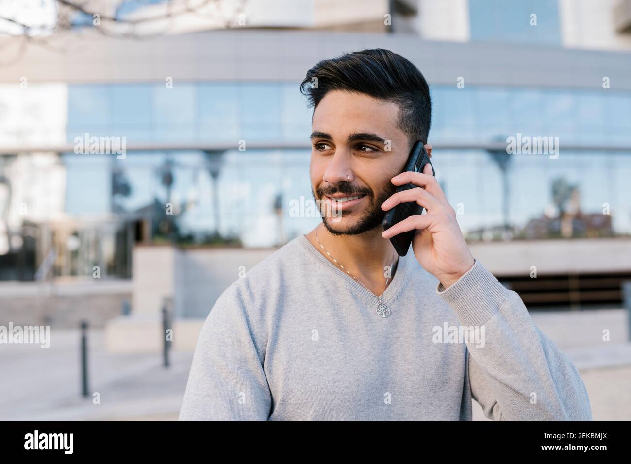 Handsome young man talking on smart phone while looking away Stock Photo