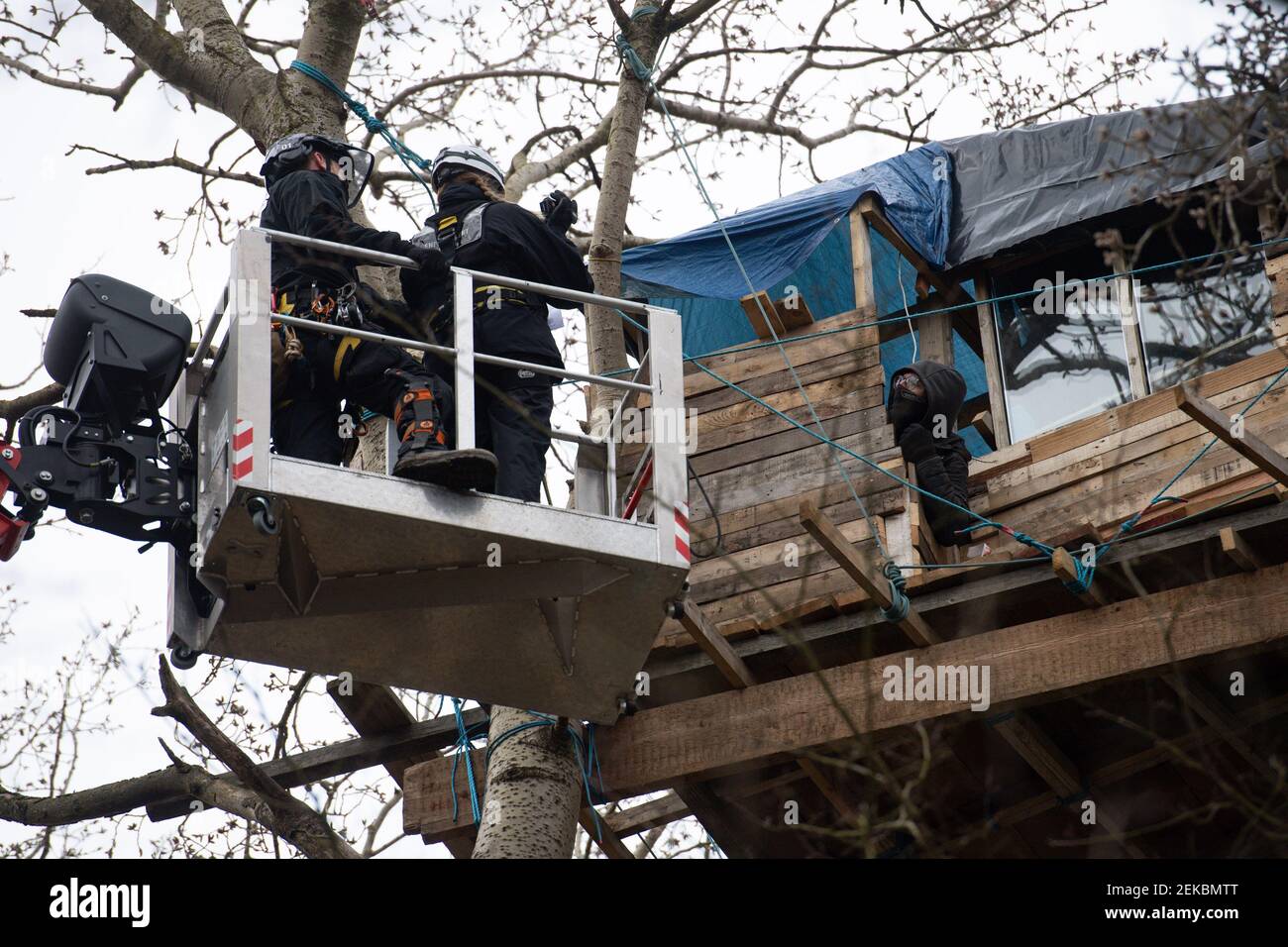 Police officers attempt to negotiate with a anti-HS2 protester, at an encampment in the ancient woodland at Poor's Piece Wood on the edge of Steeple Claydon in Buckinghamshire. Picture date: Tuesday February 23, 2021. Stock Photo