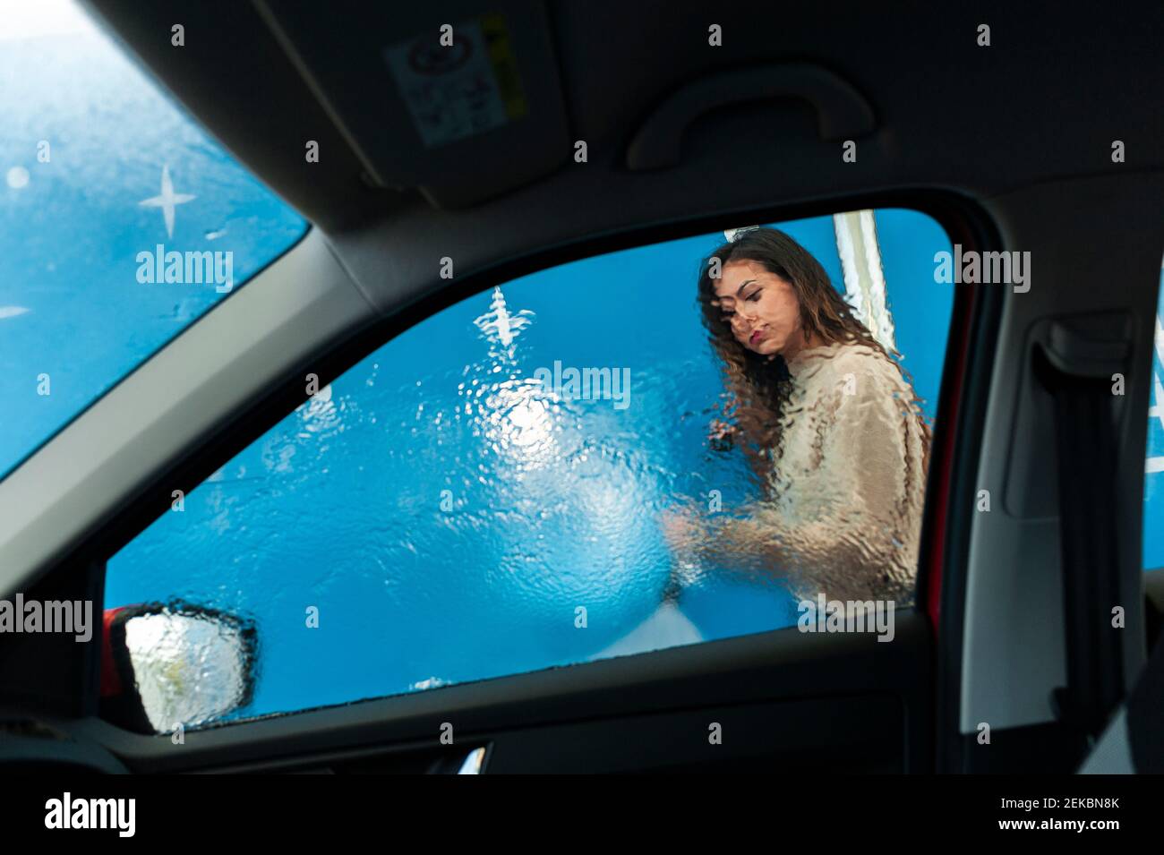 Young woman spraying water on window at car wash Stock Photo