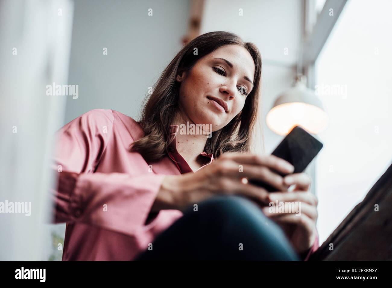 Female freelance worker using mobile phone while sitting in cafe Stock Photo