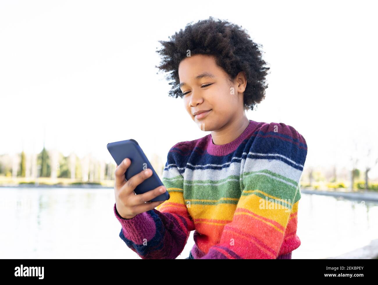 Girl using smart phone while sitting at park Stock Photo