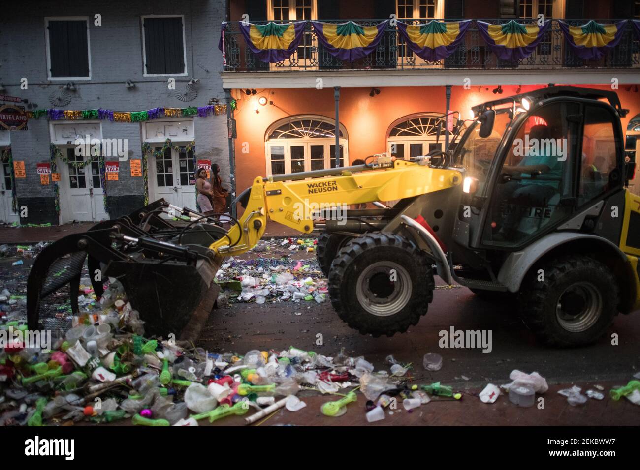 Bulldozer cleaning Trash-filled streets late night morning after Mardi Gras, New Orleans, Louisiana, USA. Bourbon Street. Stock Photo