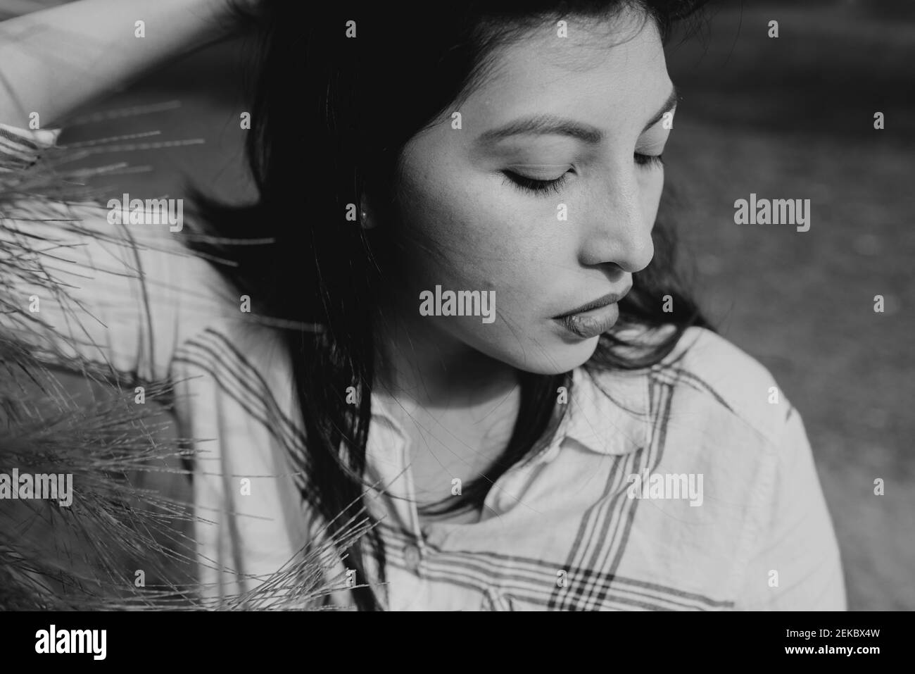 Mid adult woman with hand in hair at park Stock Photo